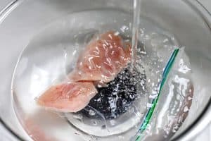 ​You can place the packaged frozen chicken in hot water to help it defrost