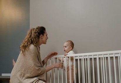 Mother and baby at the crib, checking crib mattress height - How to choose the best crib with changing table - Best crib with changing table - Baby Journey blog