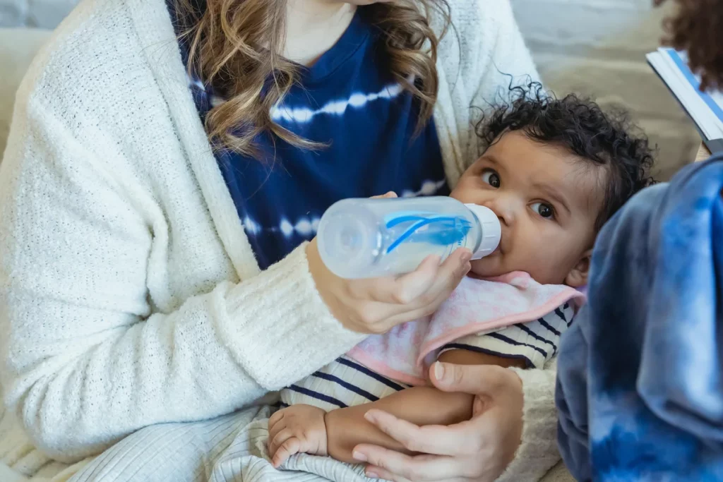 Mother feeding baby. How To Introduce Formula To Breastfed Baby - How to transition from breastmilk to formula - Baby Journey blog
