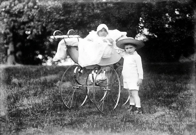 A young boy and a baby posing with an early 1900s pram with bassinet - When Were Strollers Invented History of Baby Strollers – Baby Journey