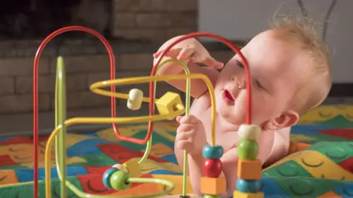  Baby playing with activity toy to develop gross motor skills. - Simple Gross Motor Activities for Infants - Baby Journey