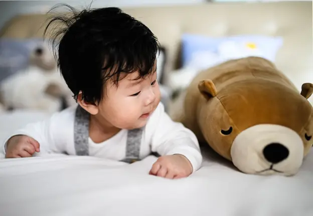 Young Asian baby boy looking at plush toy while having tummy time - Simple Gross Motor Activities for Infants - Baby Journey