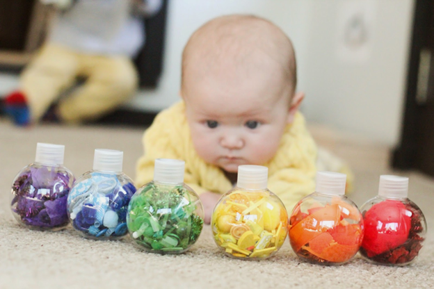 Cute baby playing with sensory bottles - Simple Gross Motor Activities for Infants - Baby Journey