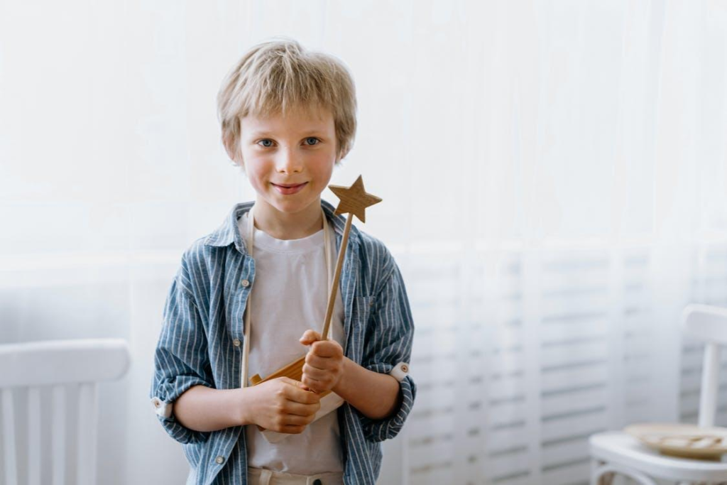Young boy smiling while holding an acting prop wooden star wand - Acting Career For Kids What Is The Best Age To Start Becoming Child Actors Kid Actors - Baby Journey