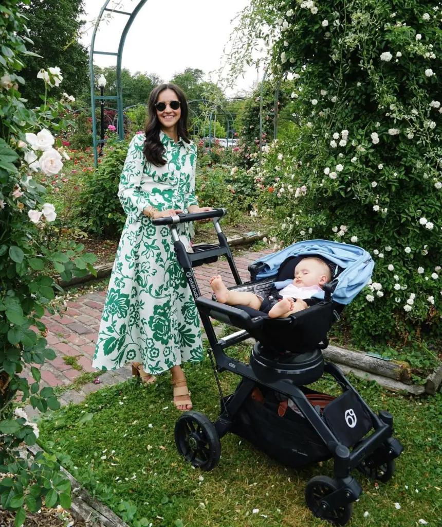 A young mother dressed in a green and white dress posing with her sleeping baby in an Orbit Baby stroller - Orbit Baby G5 Review - Baby Journey