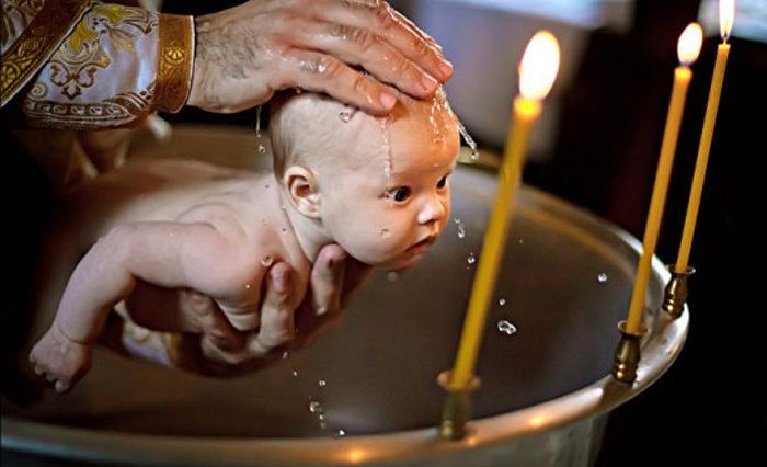 A baby being baptized by the priest - Baby dedication vs baptism - Baby Journey
