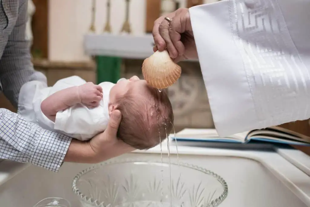 Priest bathing the baby during baptism ceremony - Baptism photoshoot, baptism photography - Baby Journey
