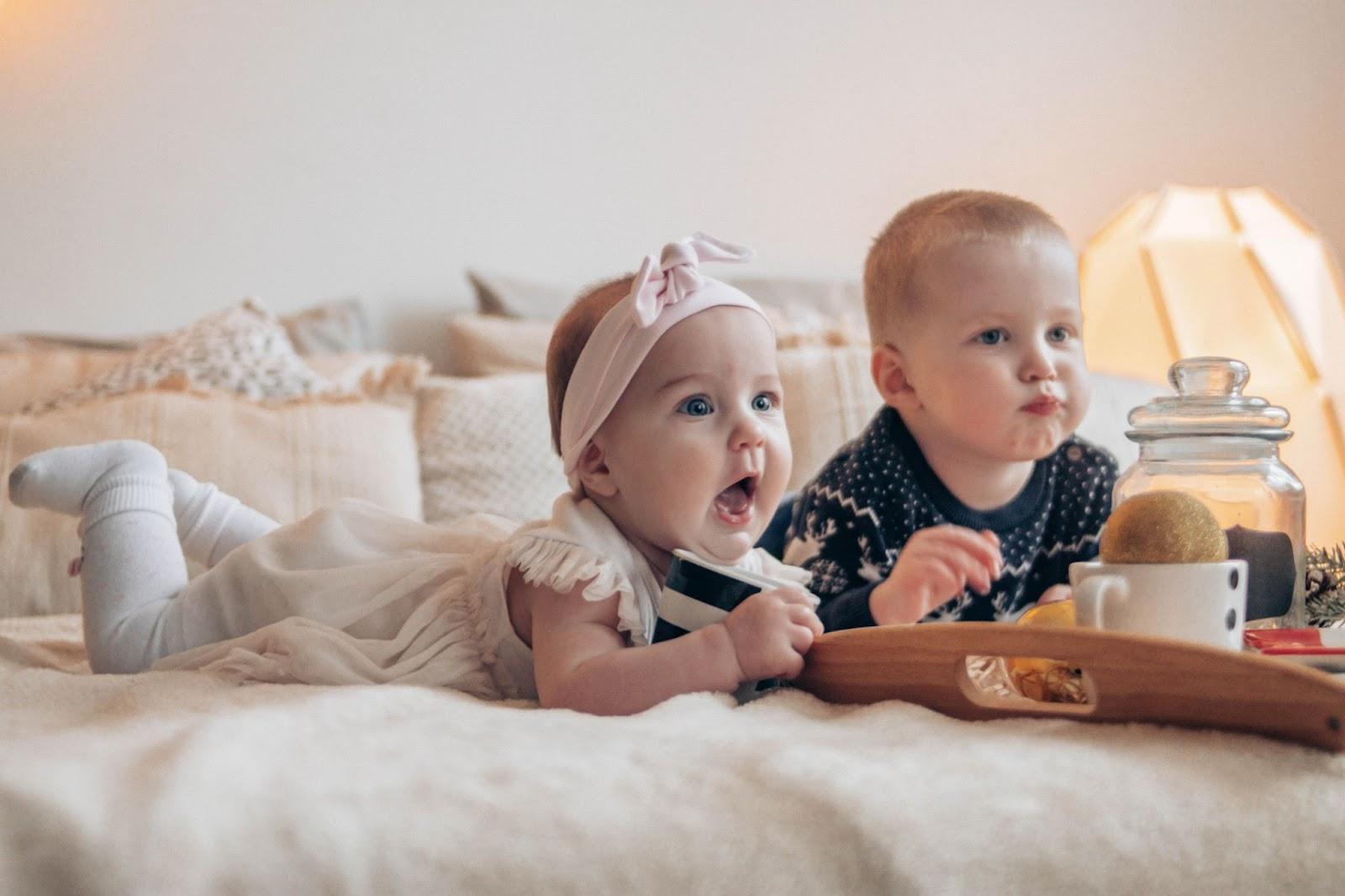 Toddler boy and his baby sister resting on the bed with a tray of snacks - Baby names that mean curious - Baby Journey