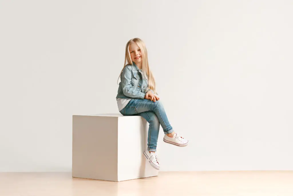 Fashionable young girl posing sitting on a wooden block - kids modeling career - Baby Journey
