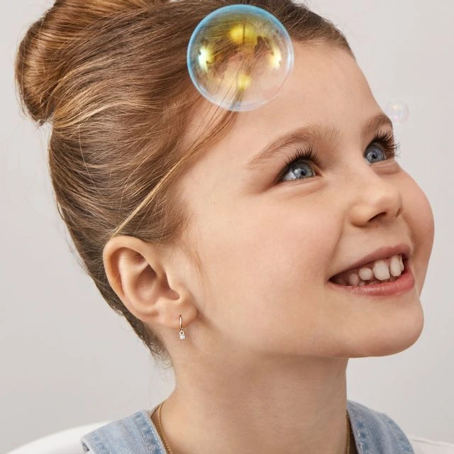 A young little girl smiling wearing a pretty tiny hoop earrings - How to choose right earrings for children kids earrings - Baby Journey