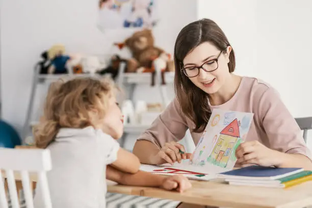 A lady home tutor showing an artwork to a young child - 10 Tips For Selecting The Best Home Tutor For Your Kid - babyjourney.net
