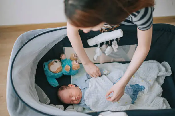 The mother covered her sleeping baby with a blanket - Baby Won't Sleep in Bassinet - Baby Journey