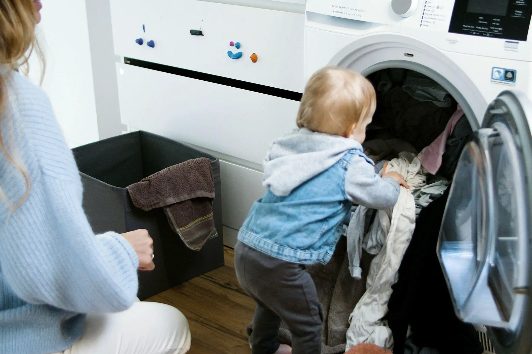 Baby puts clothes in the washing machine with mom in tow - How to Wash Baby Clothes - Baby Journey