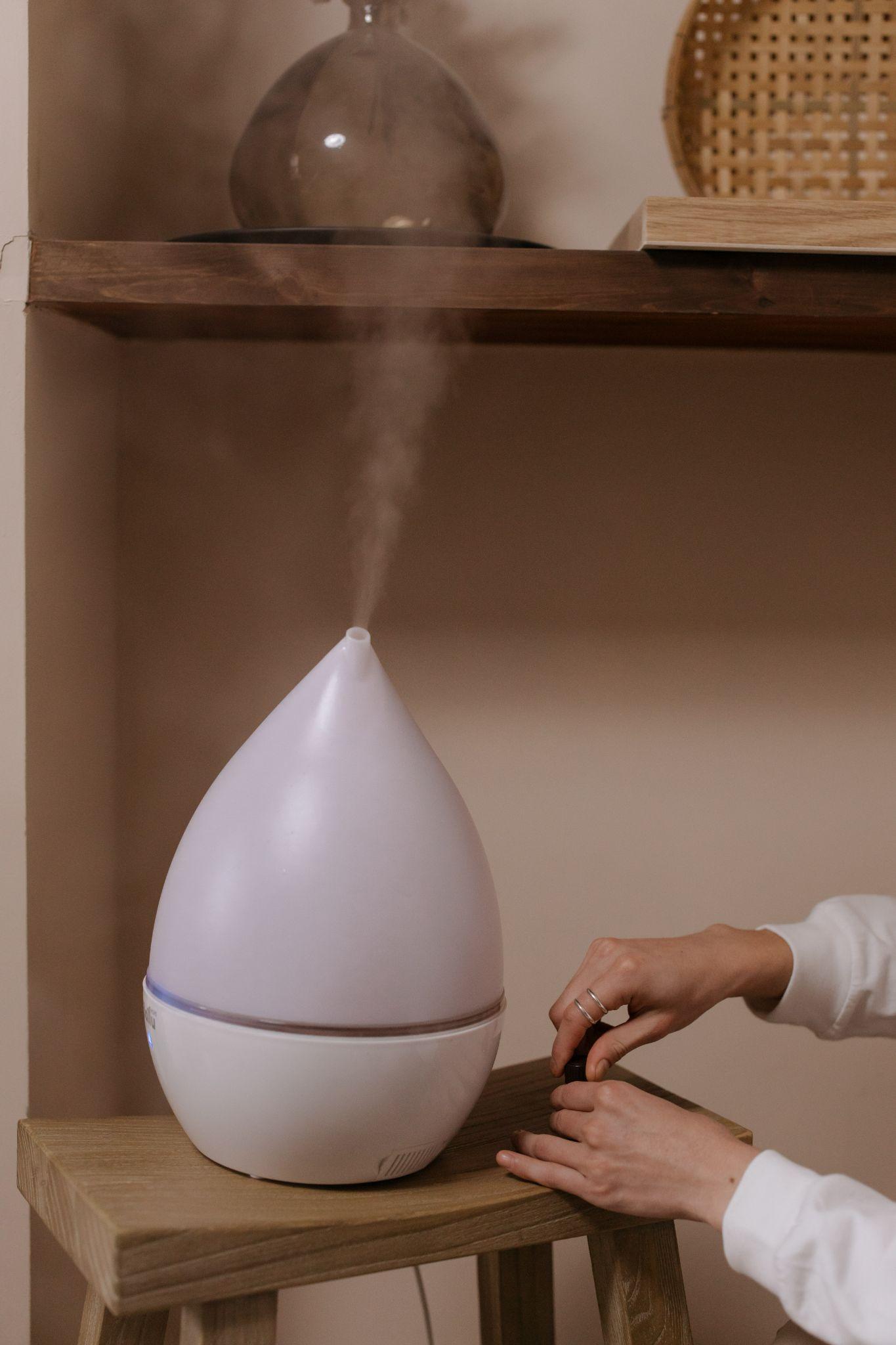 A woman adds essential oils to her humidifier - How Close Should a Humidifier Be to a Baby - Baby Journey