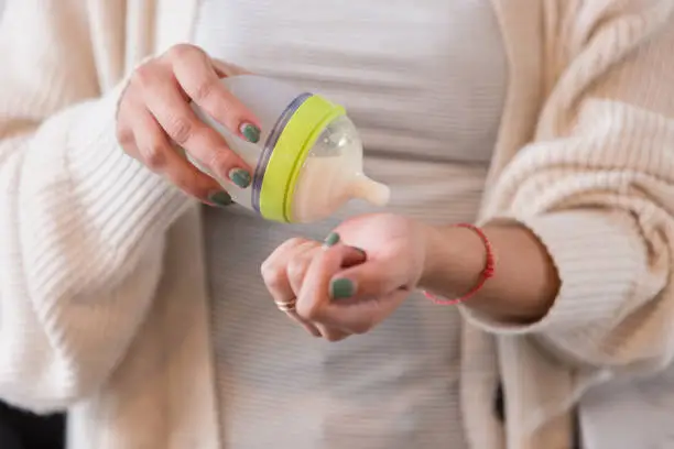 A mother testing the temperature of the milk - How Long Does It Take for Baby to Adjust to Formula - Baby Journey