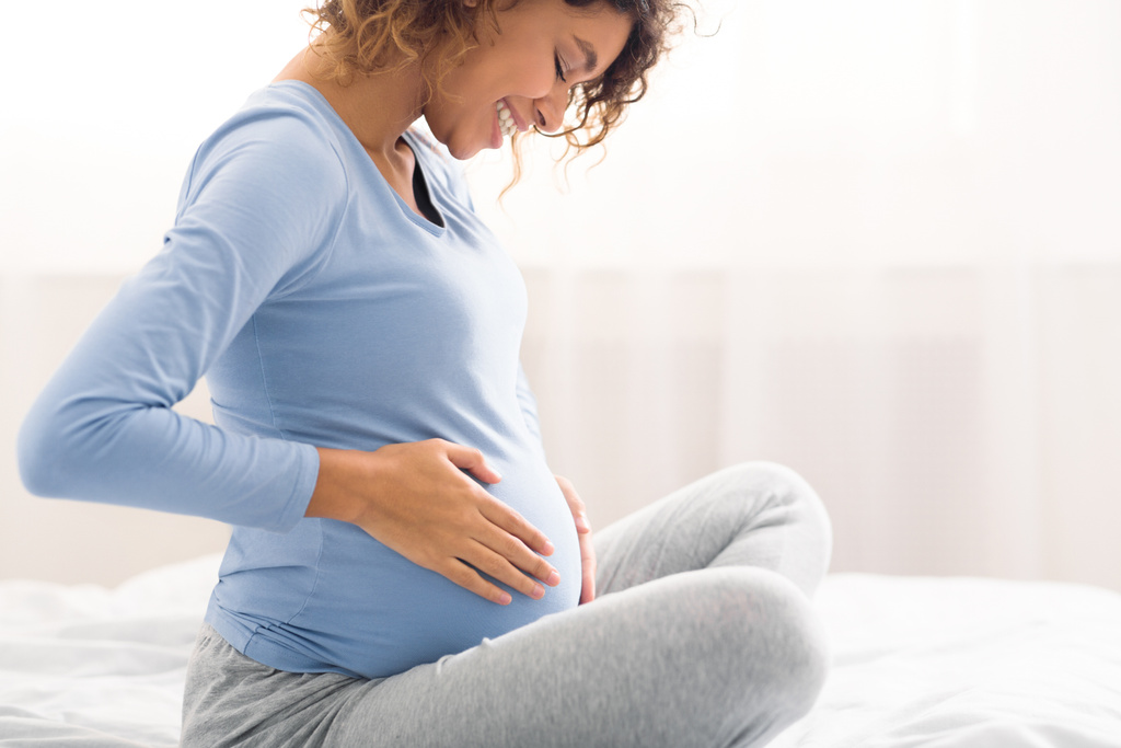 Happy pregnant mother touching her belly - The Crucial Significance of Seeking Treatment for Peripartum Mood Disturbances, Peripartum Period - Baby Journey