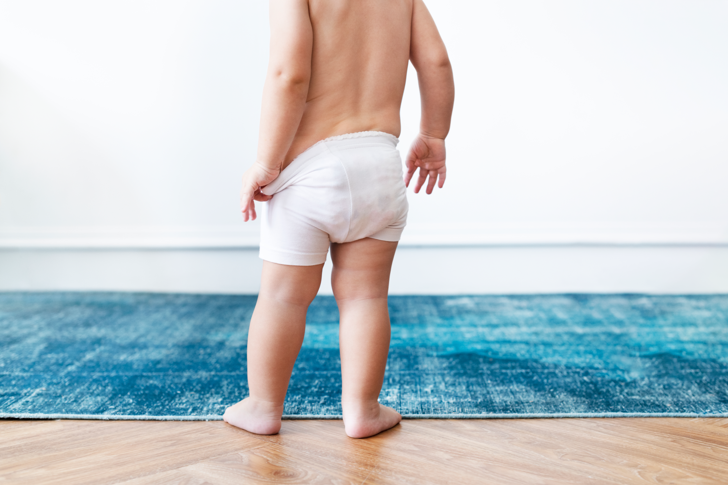 Baby getting ready to take of his diaper- How to Potty Train a Stubborn Toddler: Expert Tips and Tricks Feature Image - Baby Journey