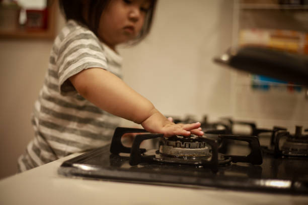 A toddler girl touching the gas stove top - How to Set Up a Childproof Kitchen - babyjourney.net