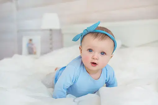 Little baby girl dressed in blue clothes with blue hairband - Best Names That Mean Blue for Girls and Boys - babyjourney.net