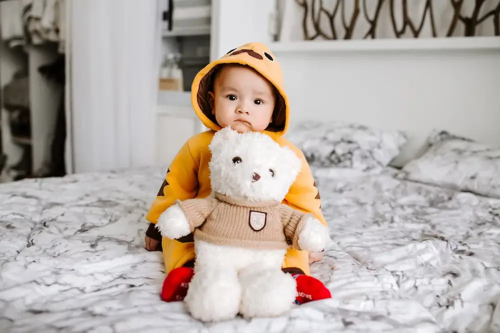 A baby boy dressed in yellow posing with a white teddy bear - 250+ Old Man Names With Timeless Appeal for Baby Boys - babyjourney.net