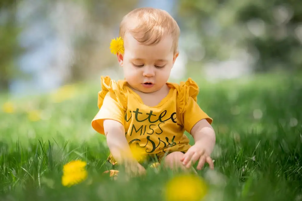 A baby dressed in yellow sitting on grass - 750+ Nature Baby Names for Girls and Boys - babyjourney.net