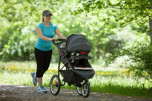 A mother in her active wear running with a baby stroller in the park - Benefits of Running With A Stroller - babyjourney.net