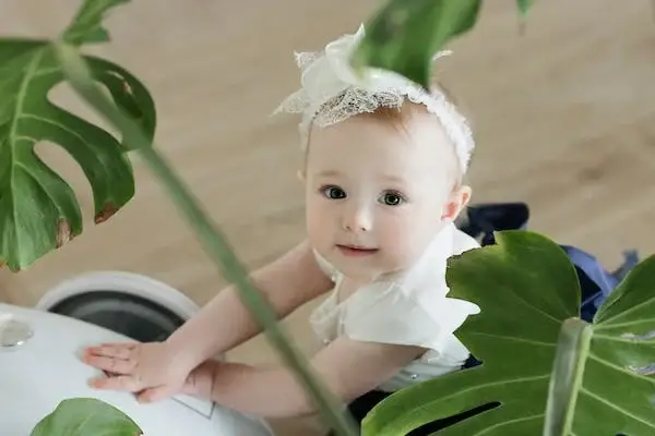 A baby girl is smiling and wearing white hairband and white dress - 150+ Names That Mean Royalty: A Comprehensive List of Royal, Ruler, Queen, and King Names - Baby Journey