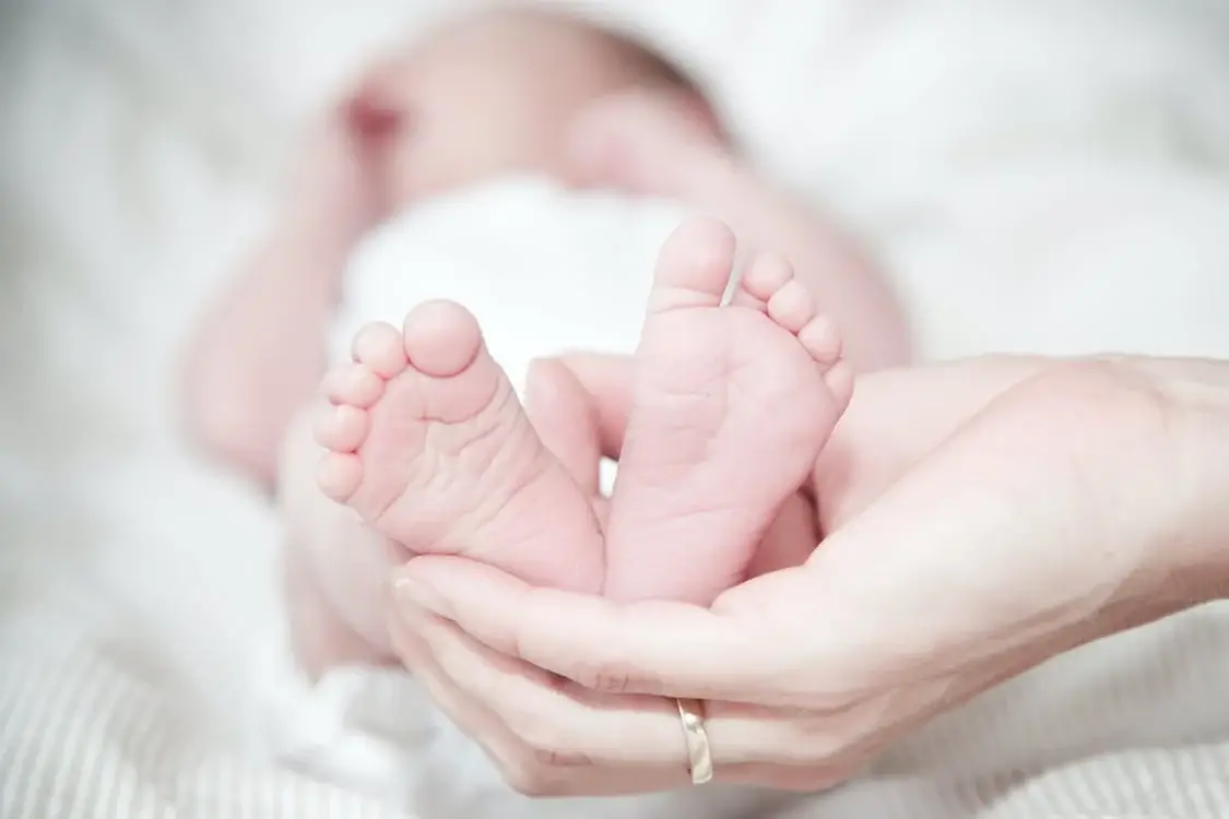 Parent hands are holding the baby feet - 150+ Names That Mean Royalty: A Comprehensive List of Royal, Ruler, Queen, and King Names - Baby Journey