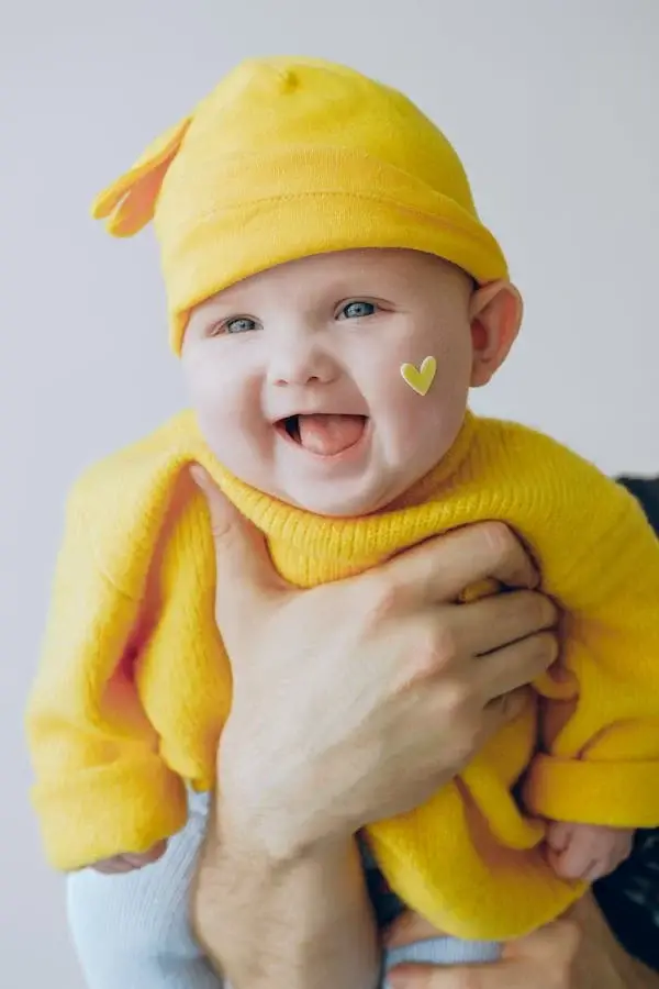 A baby wearing a yellow shirt is smiling - 230+ Middle Names for Maeve - Baby Journey