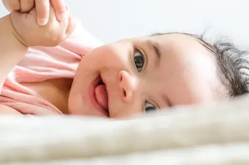 Baby laying on bed and smile - 400+ Names That Mean Beautiful for Girls and Boys - Baby Journey