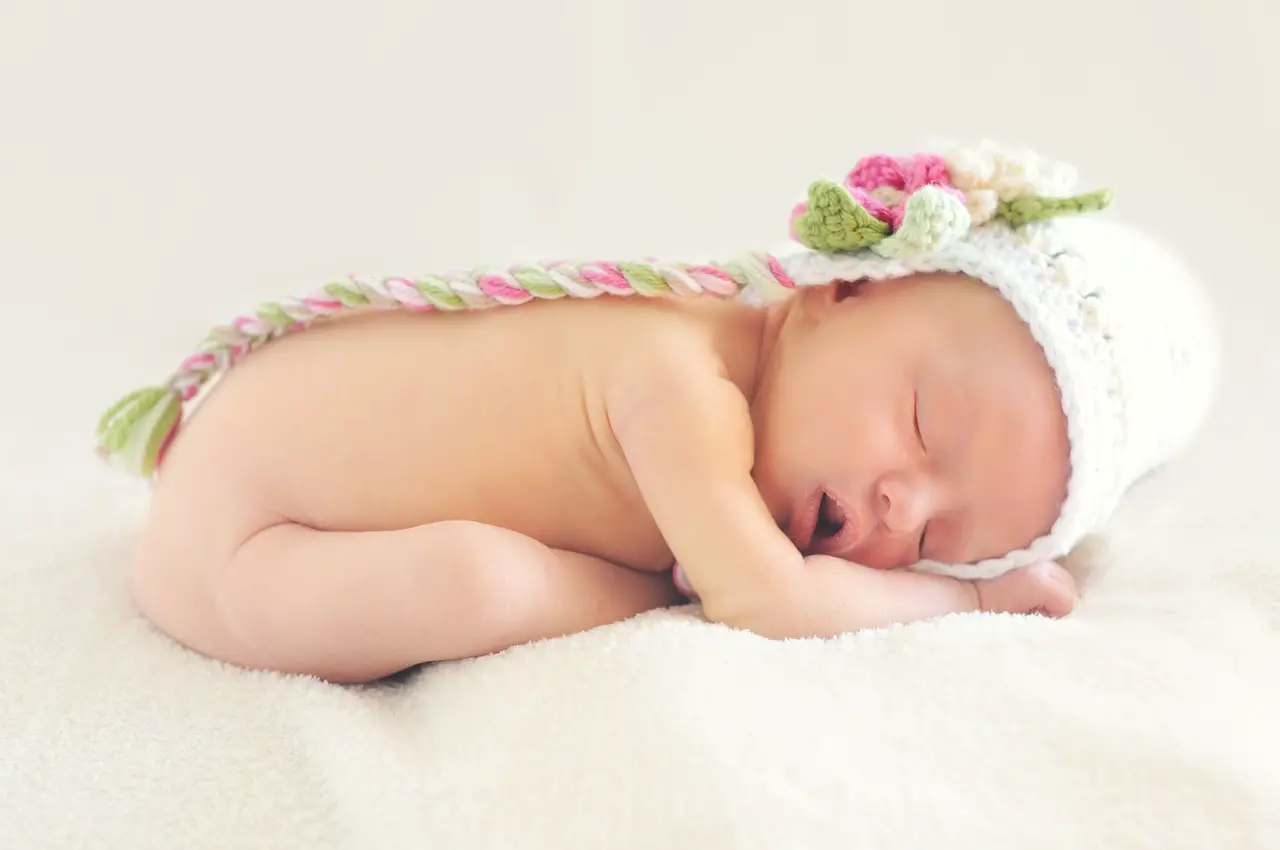 A baby, wearing colorful hats, is sleeping peacefully - 800+ Greek Baby Names - Baby Journey