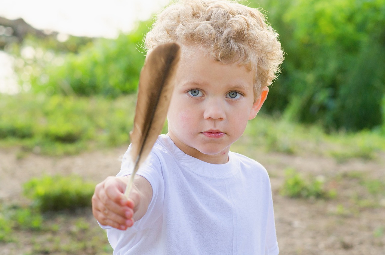 A boy holding a feather in front of the camera - 320+ Scandinavian Boy Names and Meanings - Baby Journey