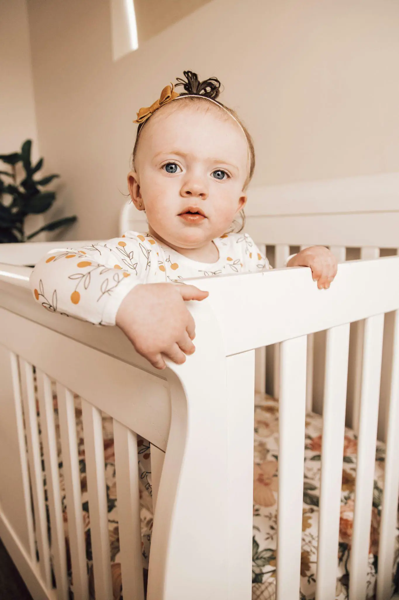 A baby girl standing in the baby cot， eyeing at the camera - 150+ Swedish Girl Names and Meanings - Baby Journey