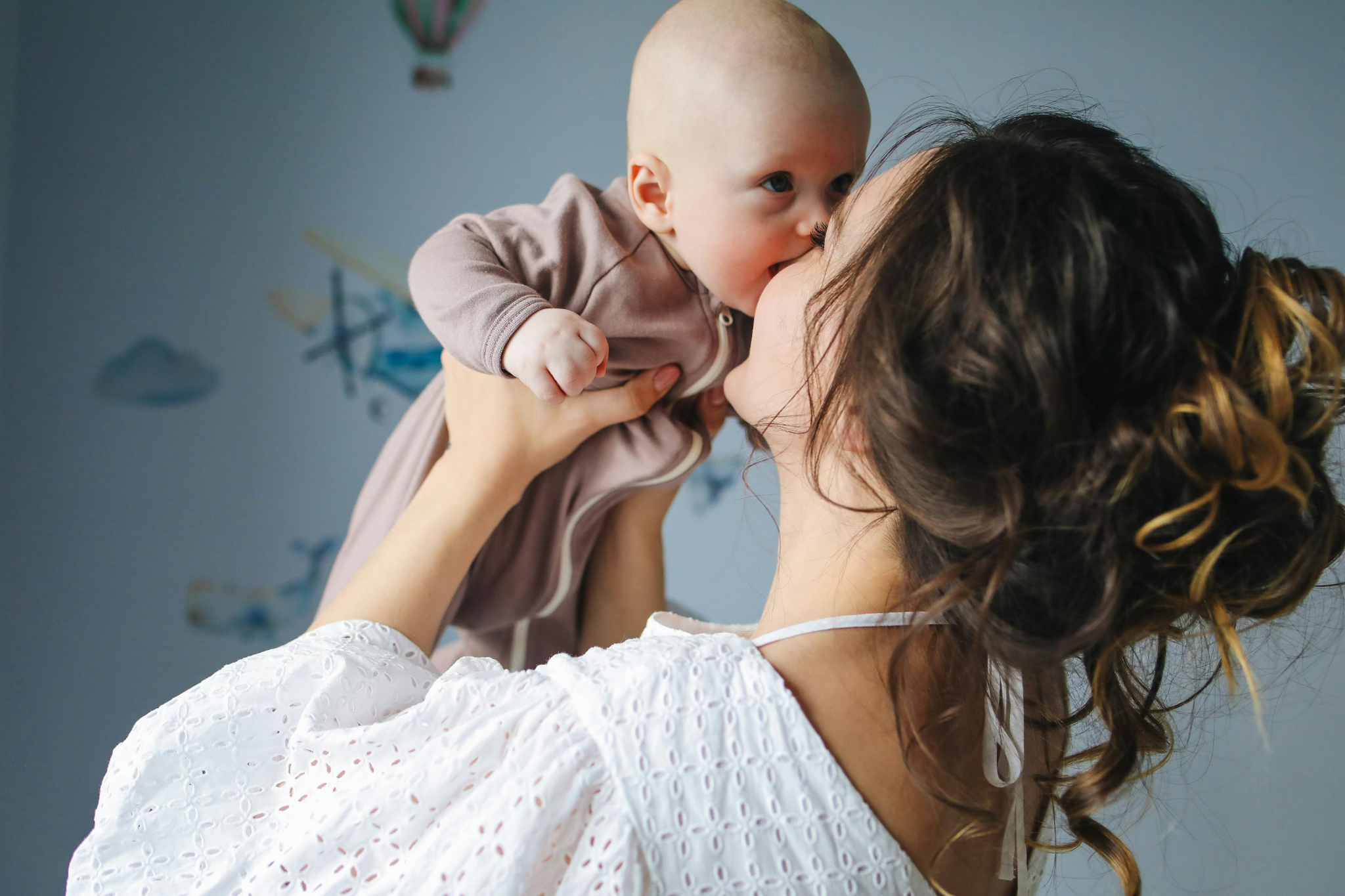 Mother hugging and kissing her cute infant - Microtia in baby - babyjourney.net